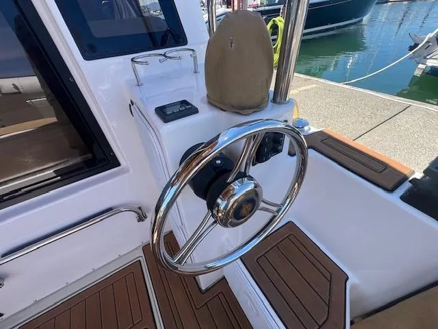 Slide: The Image of 2022 Ranger Tugs R-29 S helm with polished steering wheel and wood accents. - 14