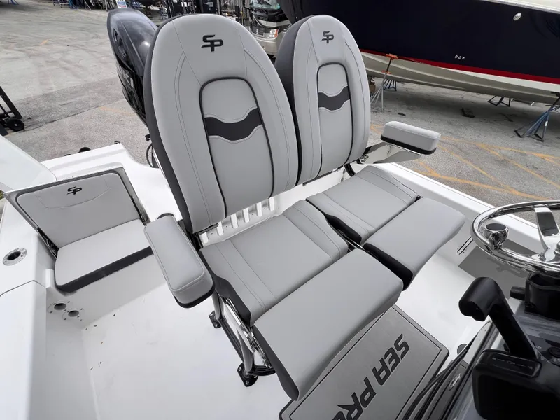 Slide: The Image of 2026 Sea Pro 230 DLX boat seats with armrests and steering wheel, docked outdoors. - 10