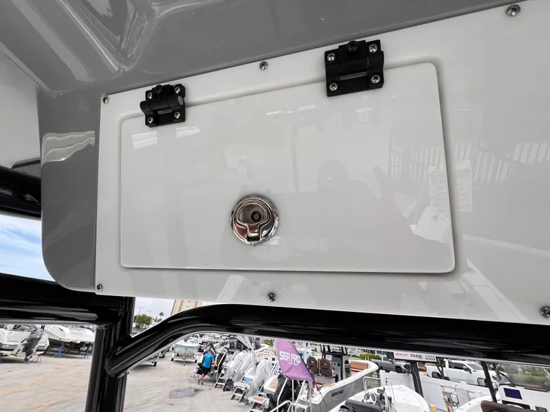 Slide: The Image of 2026 Sea Pro 230 DLX boat storage compartment with latch, displayed at a marina. - 22