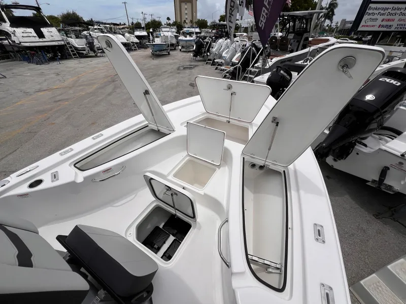Slide: The Image of 2026 Sea Pro 230 DLX boat with open storage compartments at a marina. - 28
