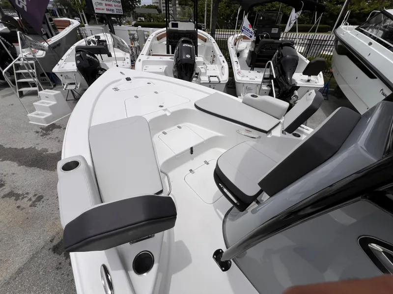 Slide: The Image of 2026 Sea Pro 230 DLX boat interior with seating and cup holders, displayed at a dealership. - 30
