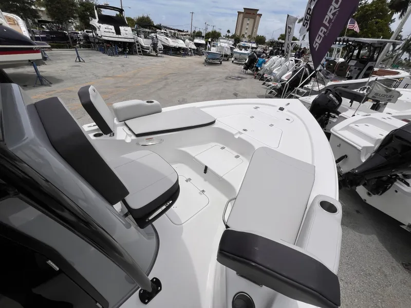Slide: The Image of 2026 Sea Pro 230 DLX boat interior with seating and storage, displayed at a marina. - 31