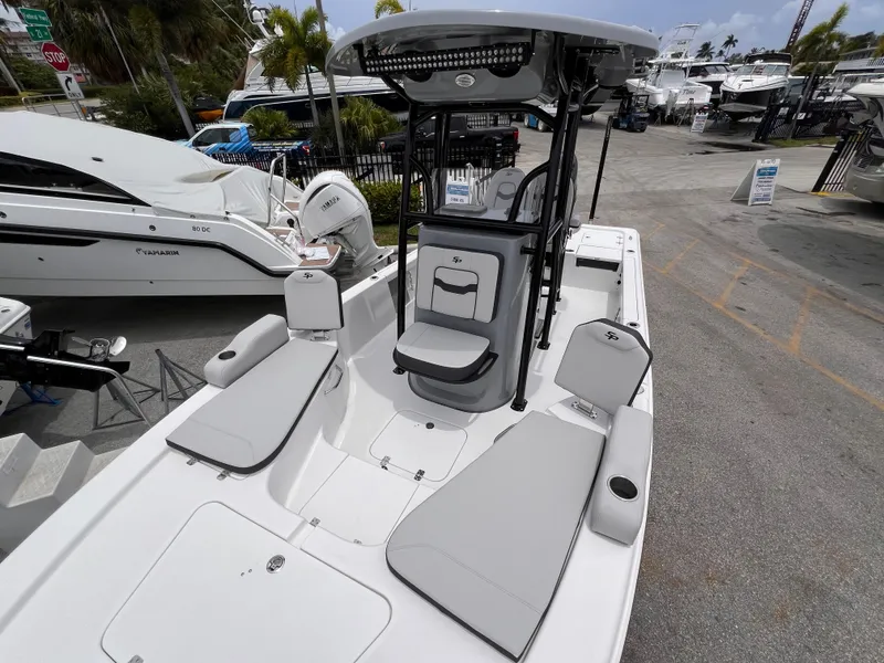 Slide: The Image of 2026 Sea Pro 230 DLX boat with sleek seating and modern design at a marina. - 33