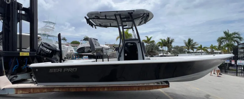 Slide: The Image of 2026 Sea Pro 230 DLX boat on a lift, with palm trees in the background. - 52