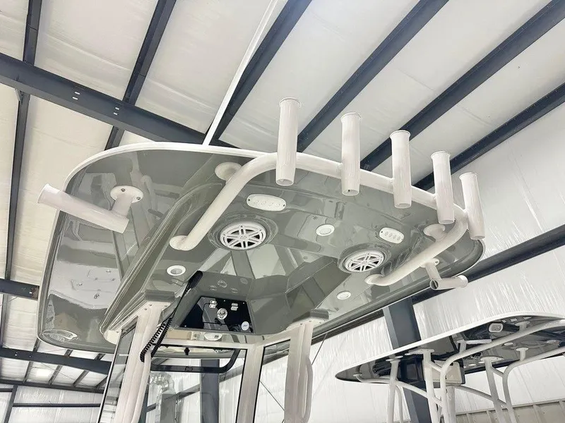 Slide: The Image of 2025 Sportsman MASTERS 247OE boat interior with rod holders and speakers in a warehouse. - 7