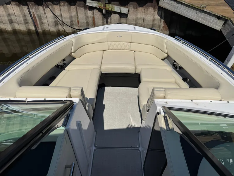 Slide: The Image of 2021 Regal 2800 boat with spacious beige seating and open deck, docked by wooden pier. - 13