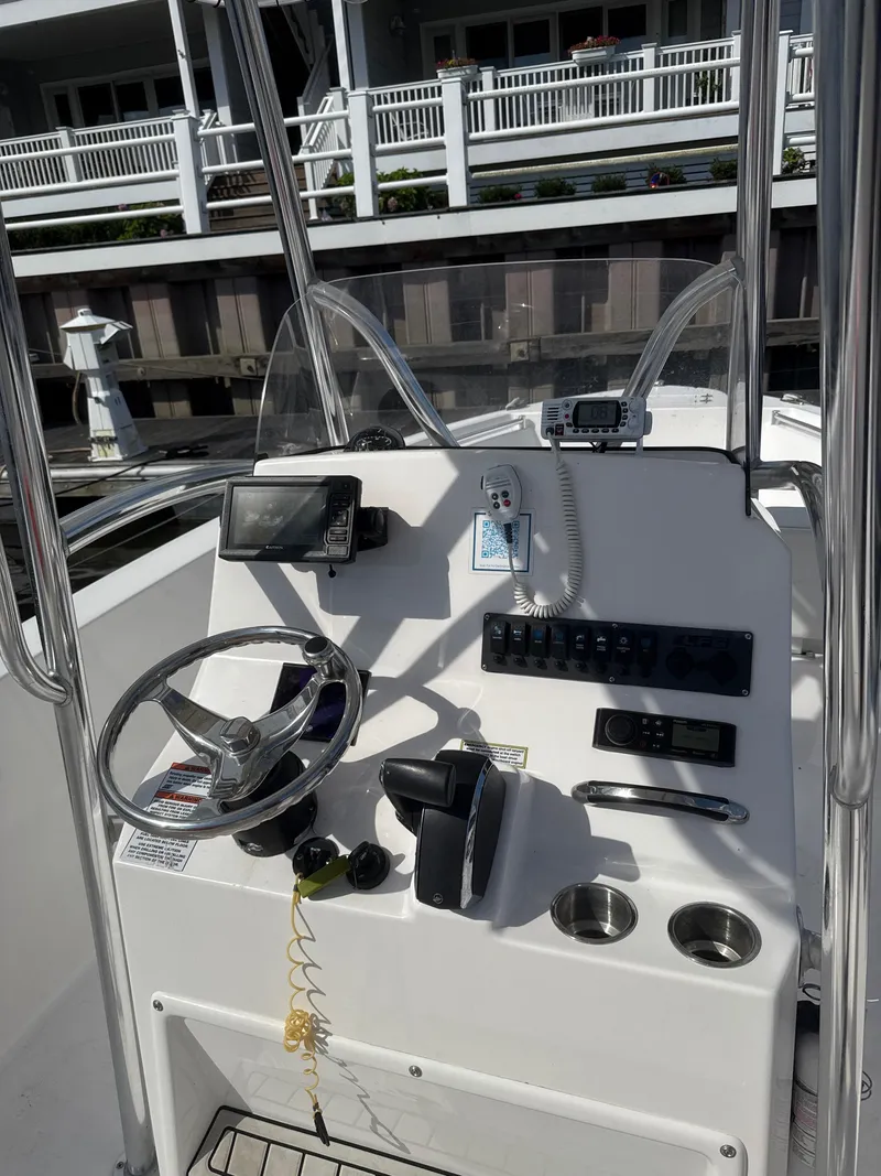 Slide: The Image of 2023 Aquasport 2200 Center Console boat dashboard with steering wheel and controls. - 5