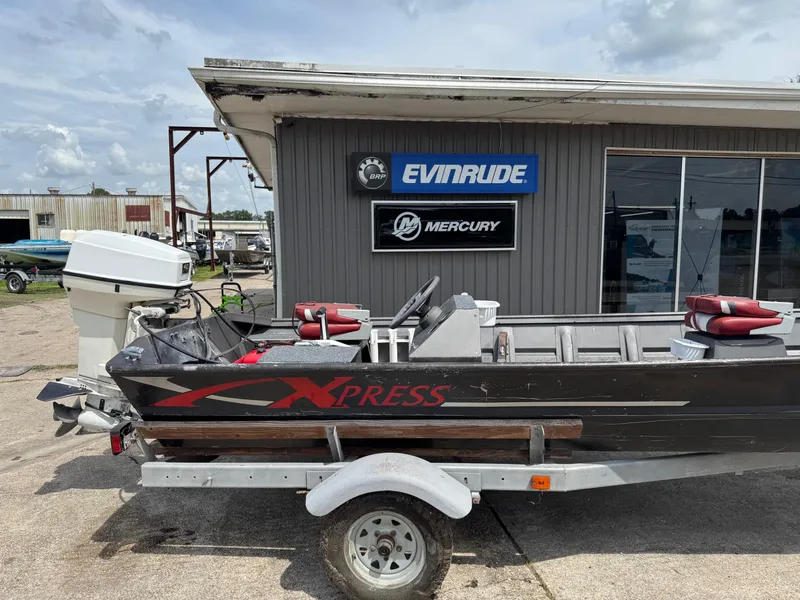 Slide: The Image of 1998 Xpress 15' boat on trailer, parked outside Evinrude and Mercury dealership. - 2