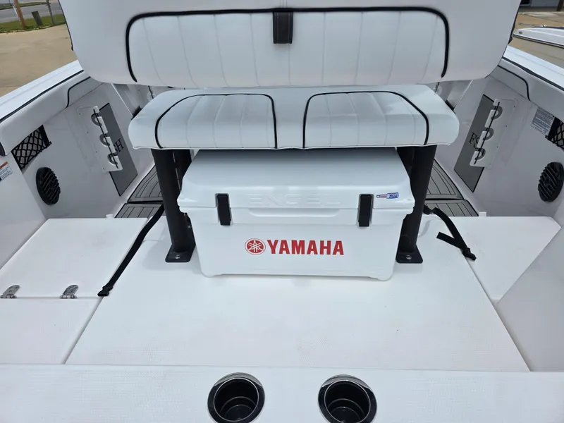 Slide: The Image of 2025 Yamaha Boats 222 FSH Sport E interior with white seating and Yamaha cooler. - 14