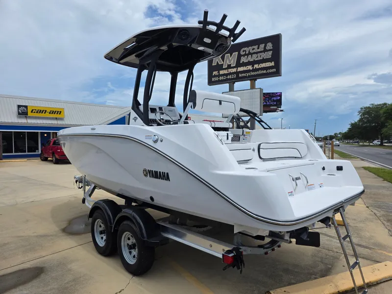 Slide: The Image of 2025 Yamaha Boats 222 FSH Sport E on trailer at dealership, clear sky background. - 2