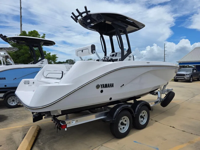 Slide: The Image of 2025 Yamaha Boats 222 FSH Sport E on trailer, sleek design, parked outdoors. - 3