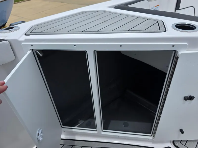 Slide: The Image of 2025 Yamaha Boats 222 FSH Sport E storage compartment with open doors, showcasing interior space. - 9