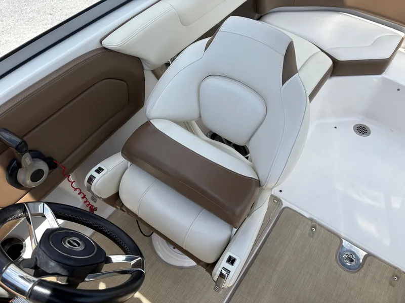 Slide: The Image of 2016 Chaparral 230 Suncoast boat interior with white and brown seating and steering wheel. - 25