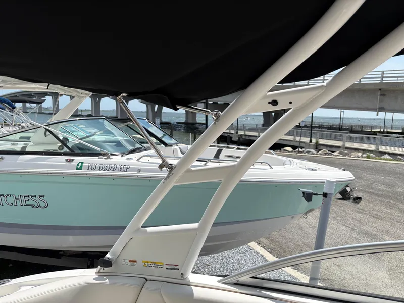 Slide: The Image of 2016 Chaparral 230 Suncoast boat docked near a bridge, featuring sleek design and white hull. - 30