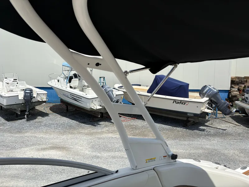 Slide: The Image of 2016 Chaparral 230 Suncoast boat with covered seating, parked near other boats. - 35