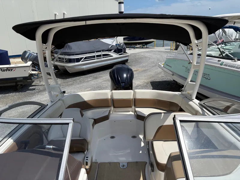 Slide: The Image of 2016 Chaparral 230 Suncoast boat interior with seating and canopy, docked near other boats. - 40
