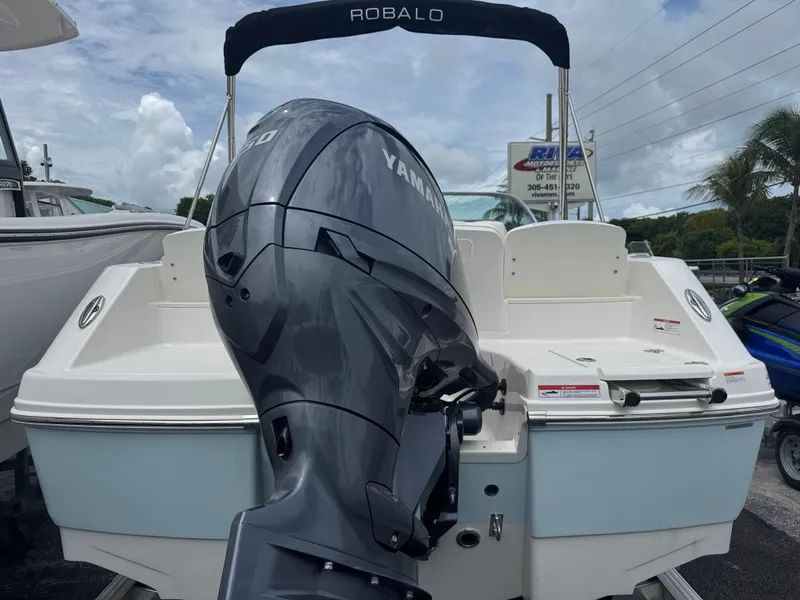 Slide: The Image of 2025 Robalo R207 Dual Console boat with Yamaha outboard motor, docked under cloudy sky. - 2