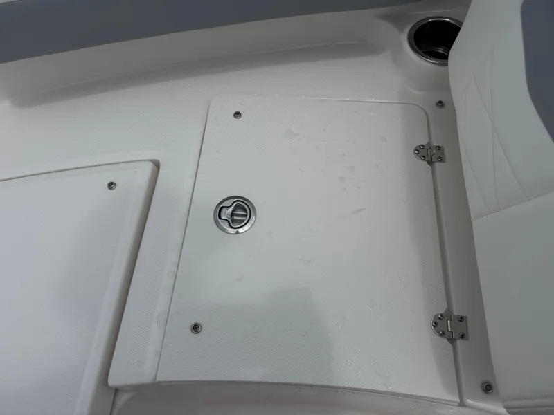 Slide: The Image of 2025 Robalo R207 Dual Console boat storage compartment with latch and hinges. - 23
