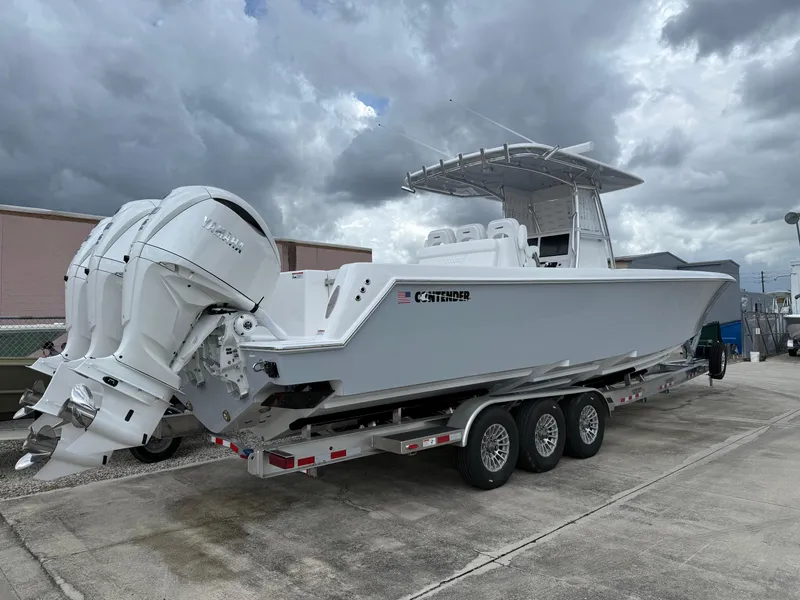 Slide: The Image of 2026 Contender 39 ST boat on trailer with triple outboard engines, under cloudy sky. - 3