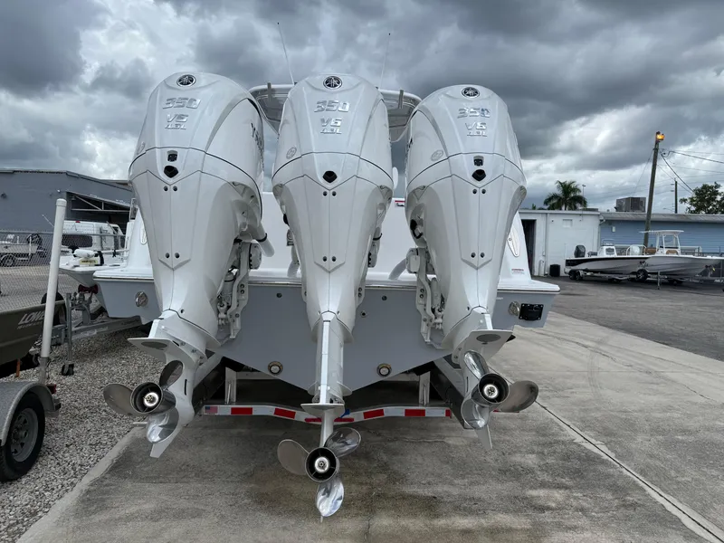 Slide: The Image of 2026 Contender 39 ST boat with triple 350 V6 outboard engines, parked under cloudy skies. - 5