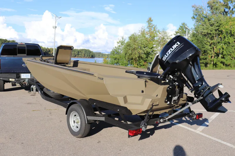 Slide: The Image of 2025 Thor 1754 Lake Hammer Tiller boat with Suzuki motor on trailer, parked near lake. - 7