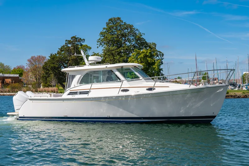 The Image of 2026 Back Cove 34O boat cruising on a sunny day near a marina. - 0