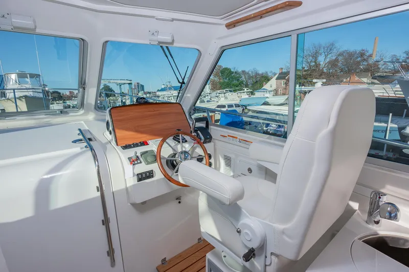 Slide: The Image of Helm of 2026 Back Cove 34O boat with white seating and wooden steering wheel. - 10