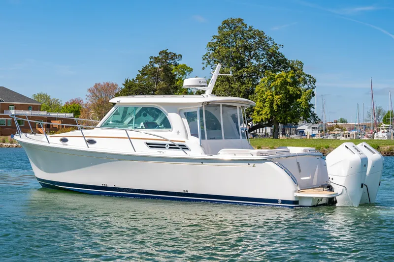 Slide: The Image of 2026 Back Cove 34O boat cruising on a sunny day near a marina. - 2