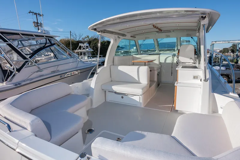 Slide: The Image of 2026 Back Cove 34O boat with spacious seating and modern design in a marina setting. - 4