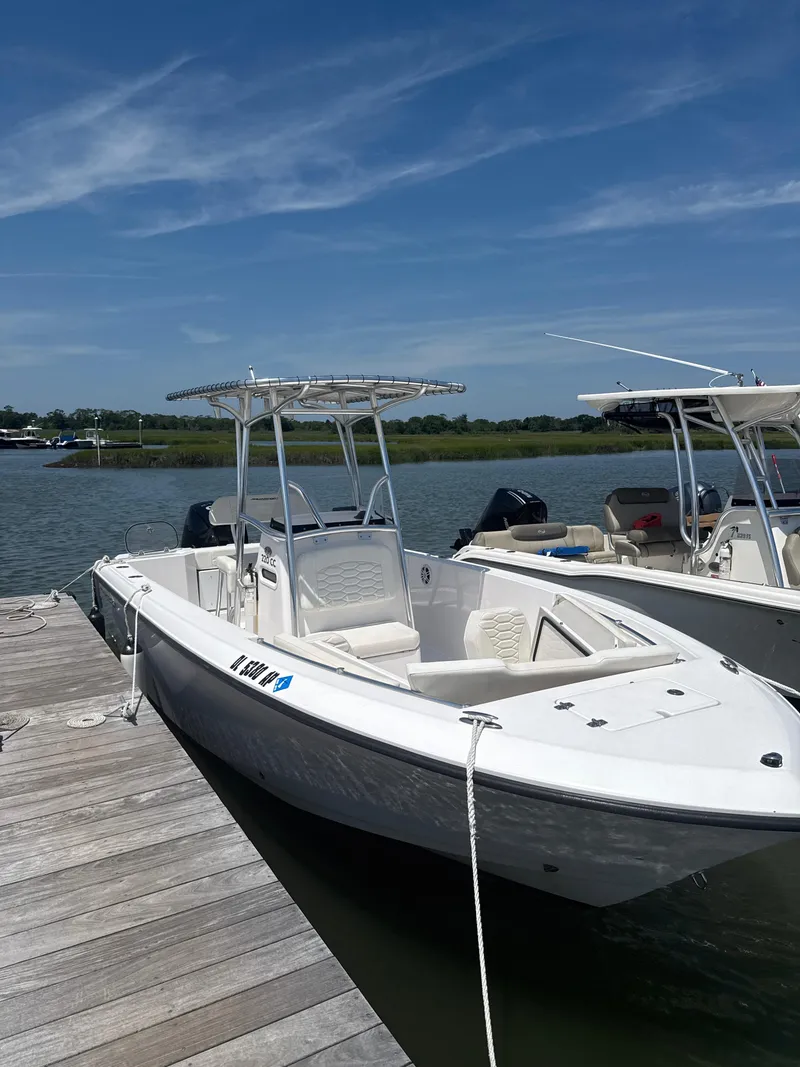 Slide: The Image of 2024 Aquasport 2200 Center Console boat docked on a sunny day. - 2
