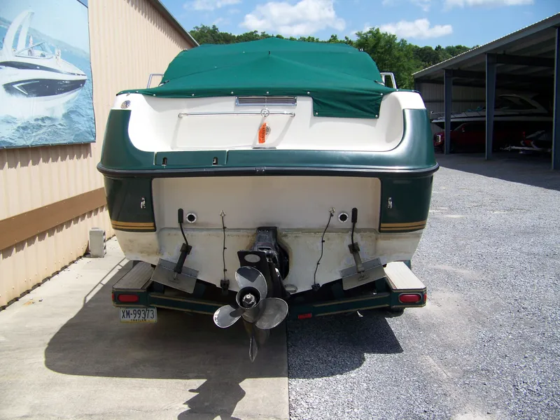Slide: The Image of 1996 Crownline 250 CR boat with green cover, parked in a storage area. - 4