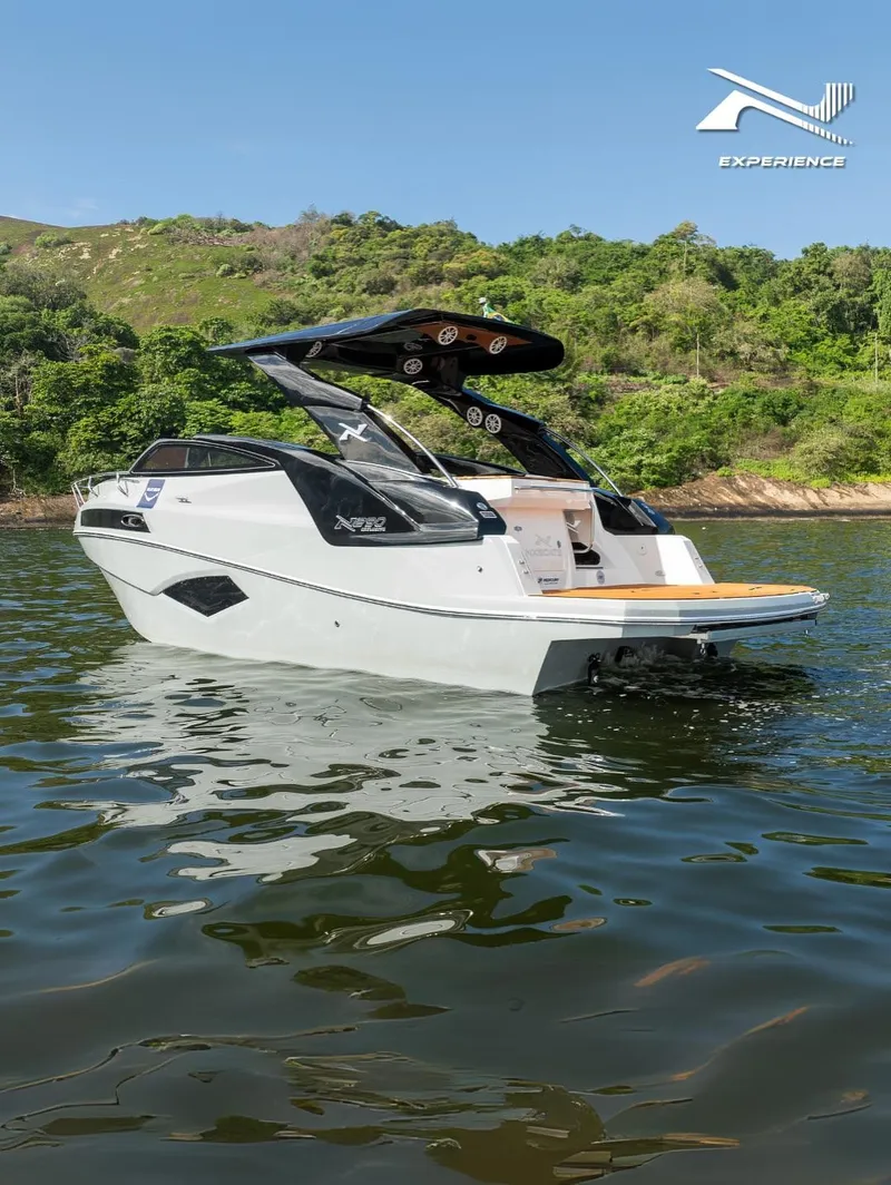 Slide: The Image of 2025 NX Boats NX290 Exclusive on water, sleek design, lush green backdrop. - 7
