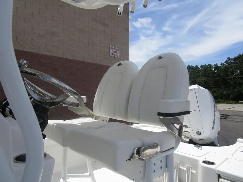 Slide: The Image of 2025 Sea Pro 230 DLX BAY boat with white seating and steering wheel, outdoors. - 14