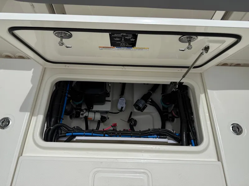 Slide: The Image of Open hatch of 2026 Boston Whaler 250 Outrage, revealing internal components and wiring. - 11