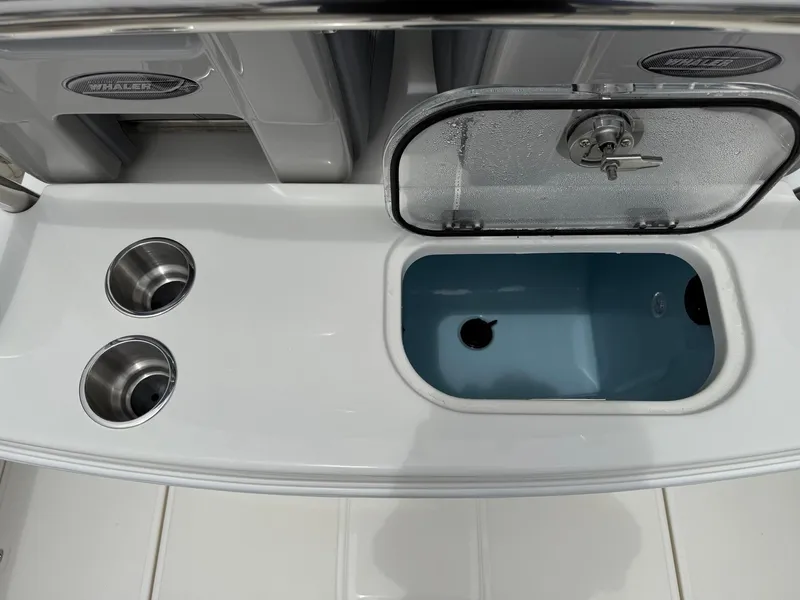 Slide: The Image of 2026 Boston Whaler 250 Outrage boat interior with open storage compartment and cup holders. - 15