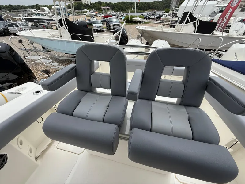 Slide: The Image of 2026 Boston Whaler 250 Outrage boat seats, gray upholstery, docked with other boats in background. - 18
