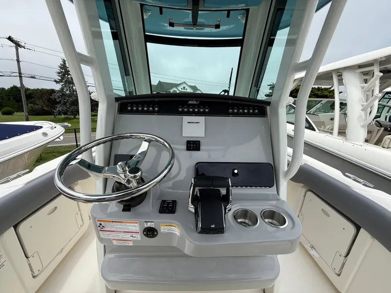 Slide: The Image of 2026 Boston Whaler 250 Outrage helm with steering wheel and control panel. - 19