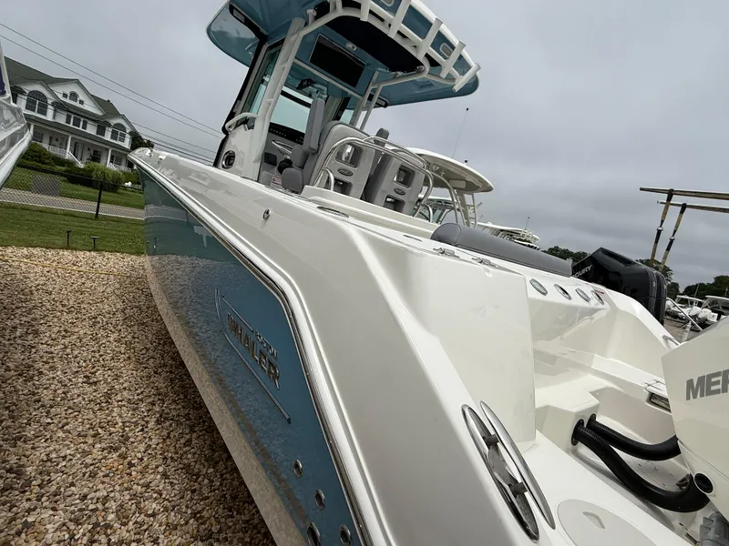 Slide: The Image of 2026 Boston Whaler 250 Outrage boat displayed on gravel, showcasing sleek design and modern features. - 3