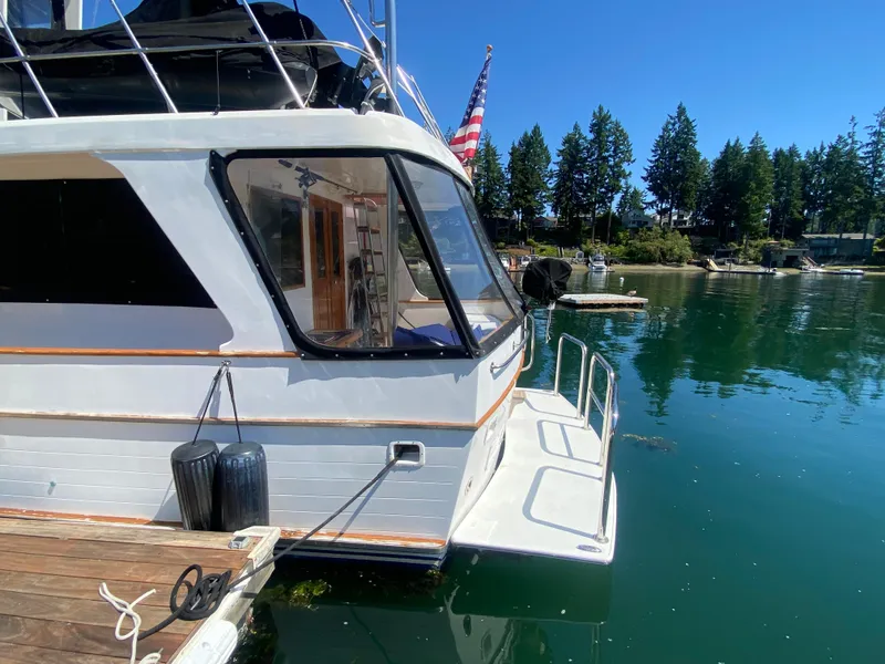 Slide: The Image of 1982 C & L Sea Ranger yacht docked on a serene lake with clear blue skies. - 23