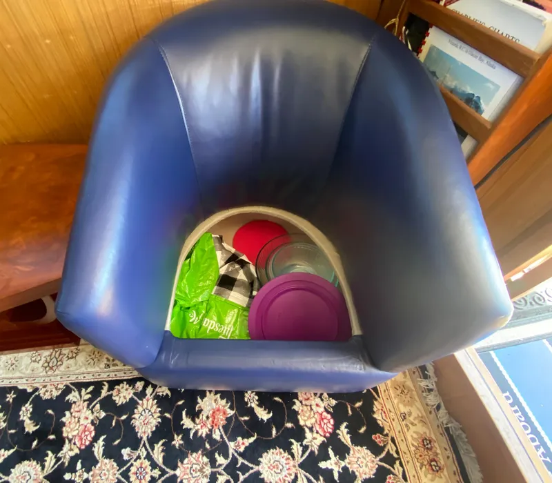 Slide: The Image of Blue chair with storage, containing plastic containers and a checkered cloth, on a patterned rug. - 36