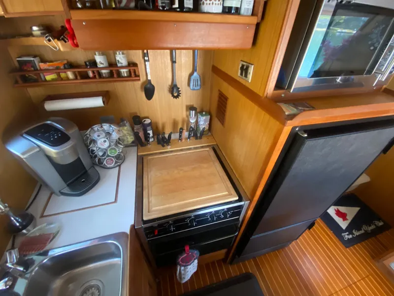Slide: The Image of Compact kitchen in 1982 C & L Sea Ranger boat with appliances and wooden cabinetry. - 44