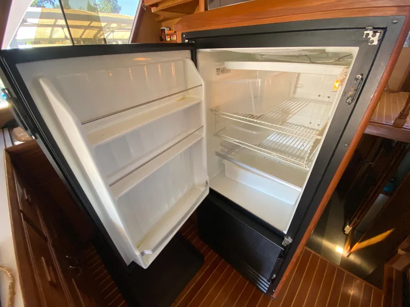 Slide: The Image of Open refrigerator inside 1982 C & L Sea Ranger boat, showcasing interior shelves. - 47