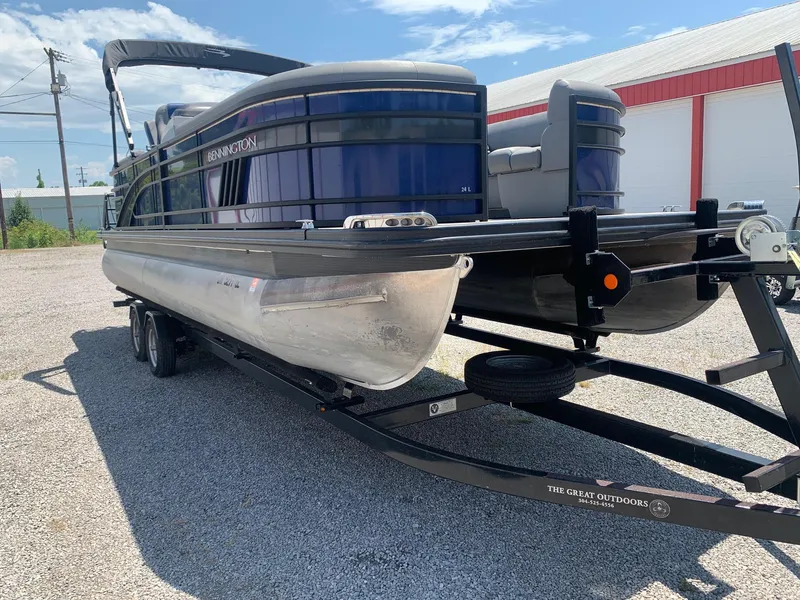 Slide: The Image of 2021 Bennington 24 LSR pontoon boat on trailer, parked outdoors under blue sky. - 4