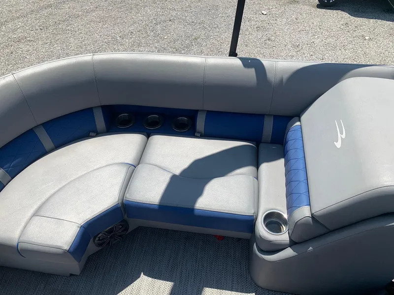 Slide: The Image of 2021 Bennington 24 LSR boat interior with gray and blue seating, cup holders, and speaker. - 9