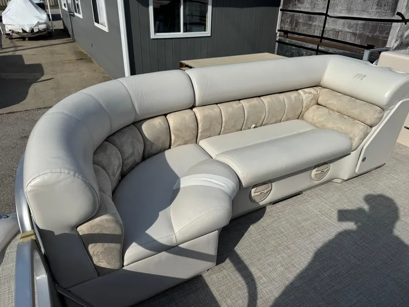 Slide: The Image of 2006 Manitou 24 Legacy boat interior with curved beige seating and carpeted flooring. - 1