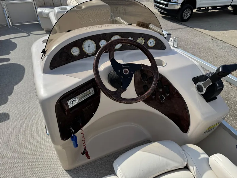 Slide: The Image of 2006 Manitou 24 Legacy boat dashboard with steering wheel and control panel. - 8