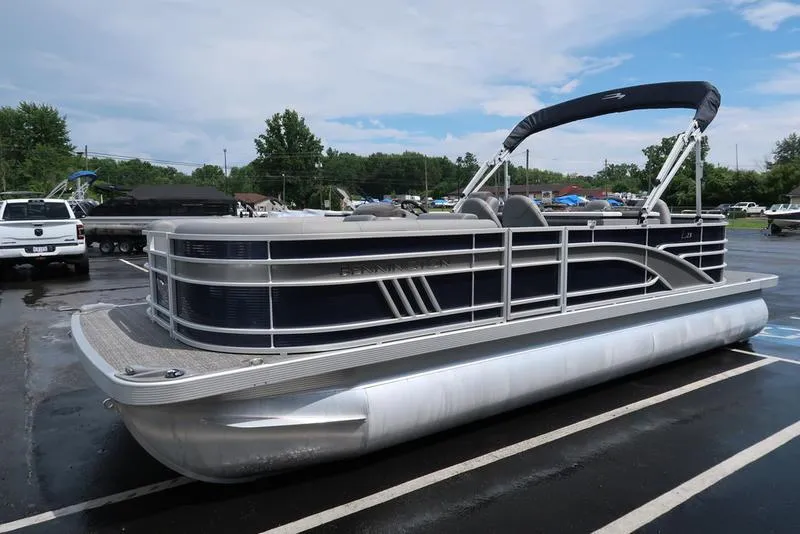 Slide: The Image of 2024 Bennington L Entertainment 23 LPD pontoon boat parked on wet pavement. - 6