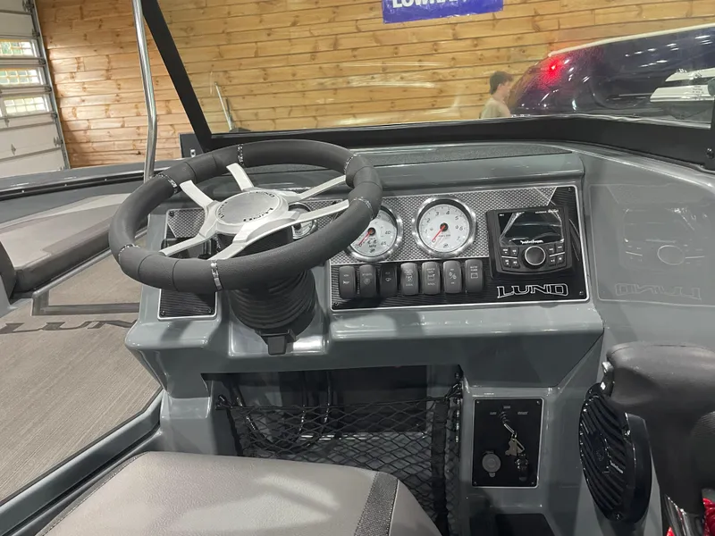 Slide: The Image of 2025 Lund 185 Impact GL boat dashboard with steering wheel and control panel. - 10