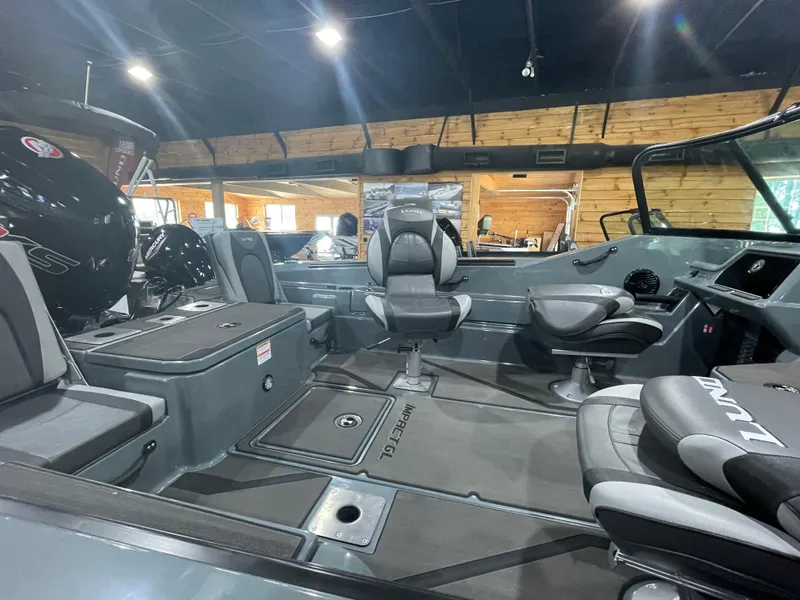 Slide: The Image of 2025 Lund 185 Impact GL boat interior with modern seating and controls in showroom. - 12