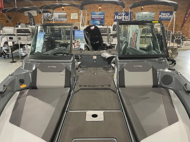 Slide: The Image of 2025 Lund 185 Impact GL boat interior in showroom, featuring dual consoles and seating. - 5
